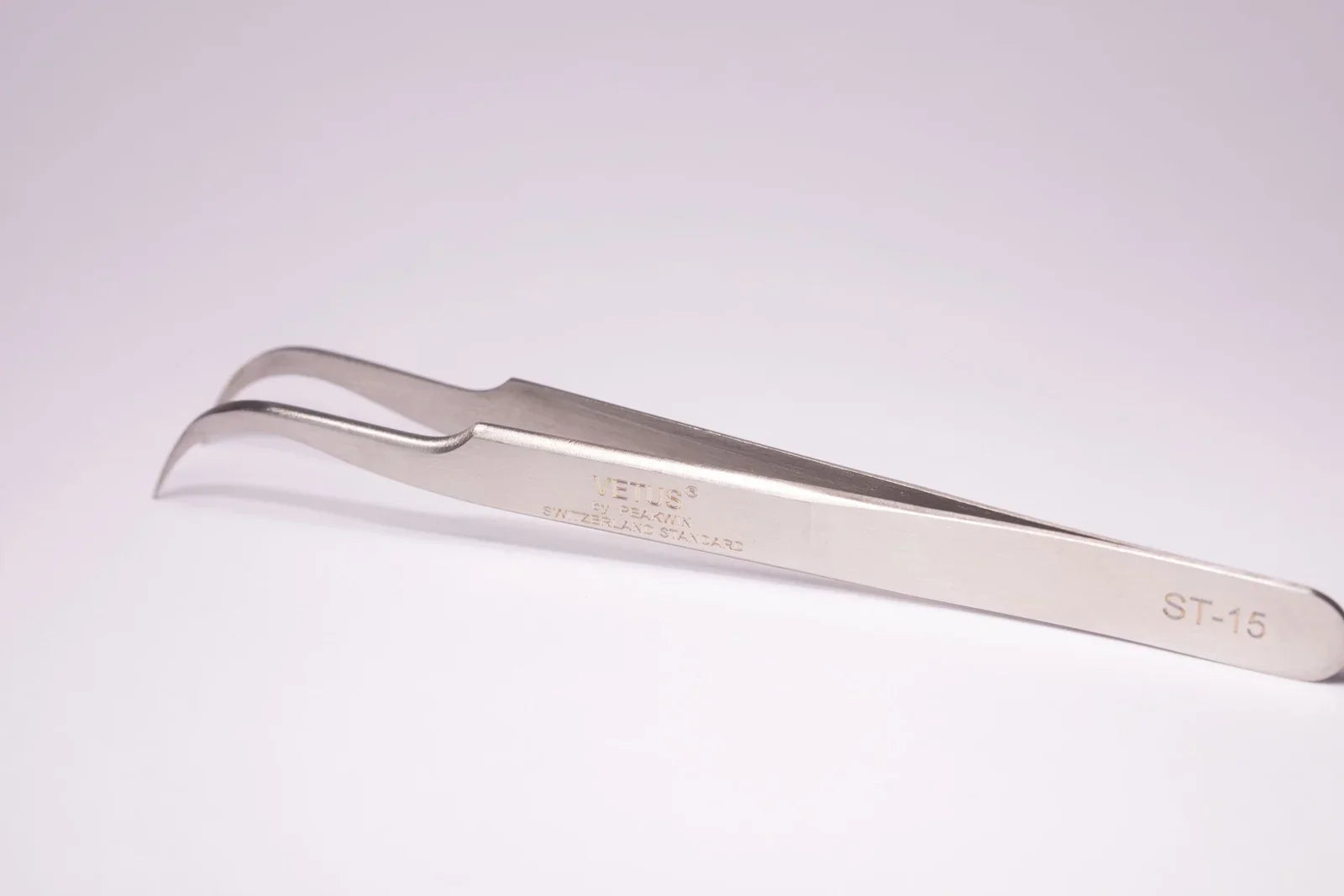Silver stainless steel tweezers with curved pointed tips and engraved markings ideal for hypoallergenic adhesive glue use