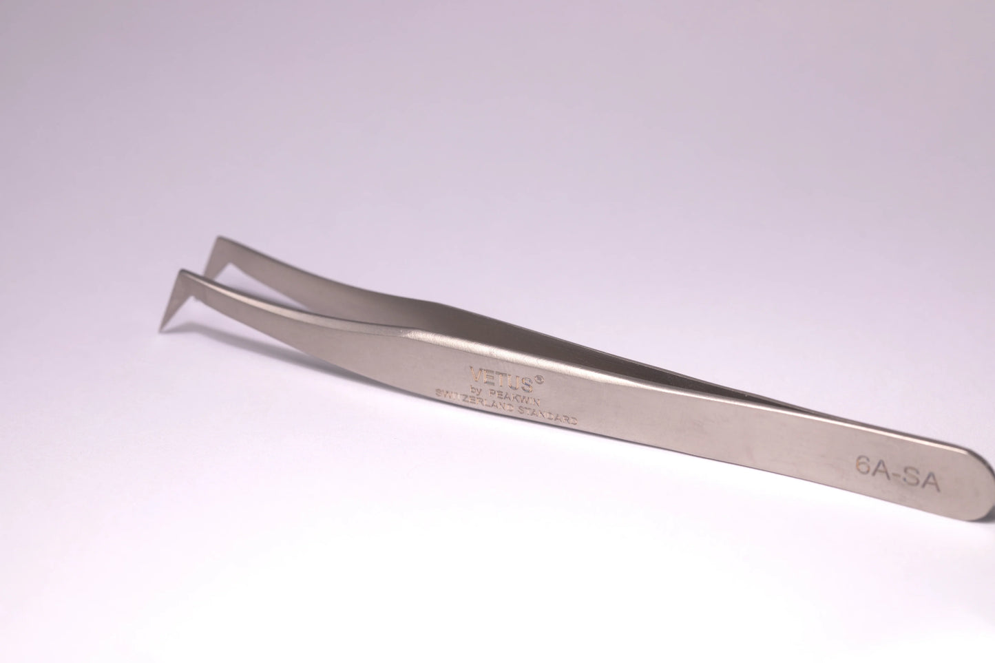 Silver precision tweezers with angled tips and engraved markings ideal for minimizing allergic reactions in lash techs malta